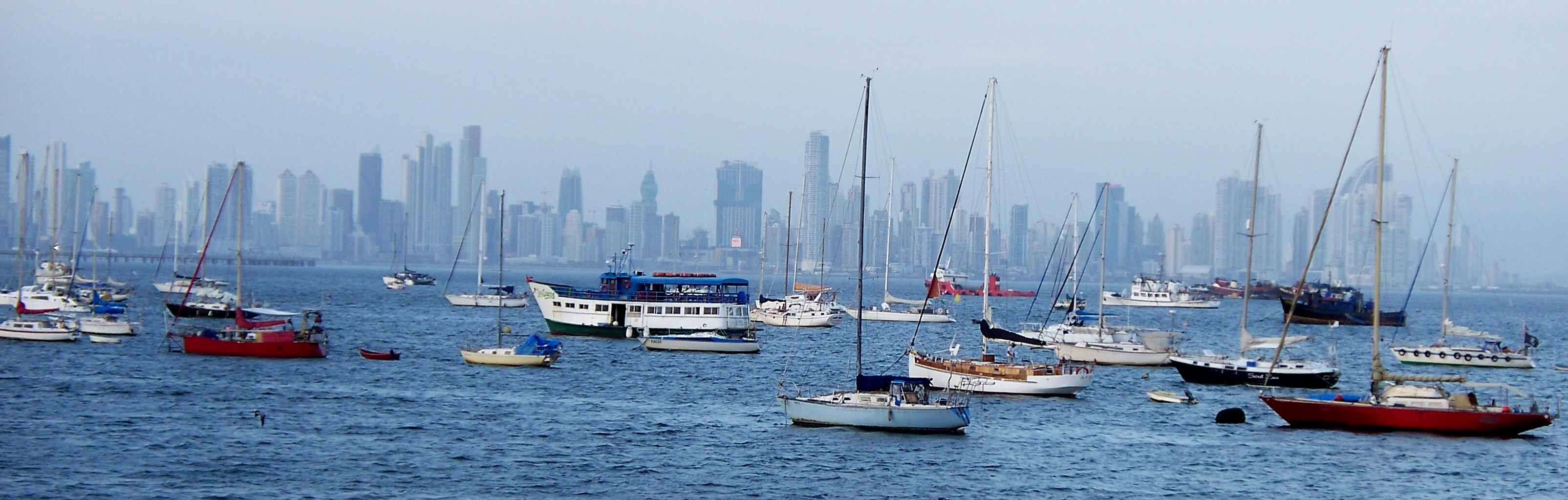 Yachts bob at anchor on the Amador Causeway. Beyond is the shimmering haze of the Panama City skyline.